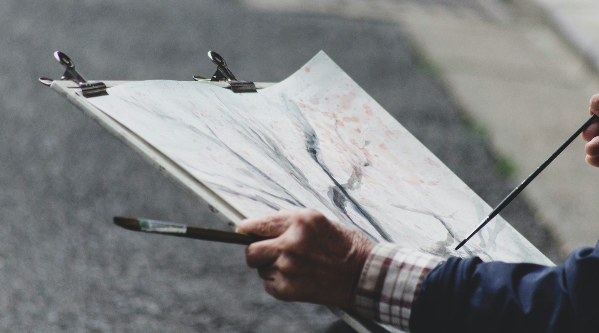 person holding paint brush while looking on white printer paper